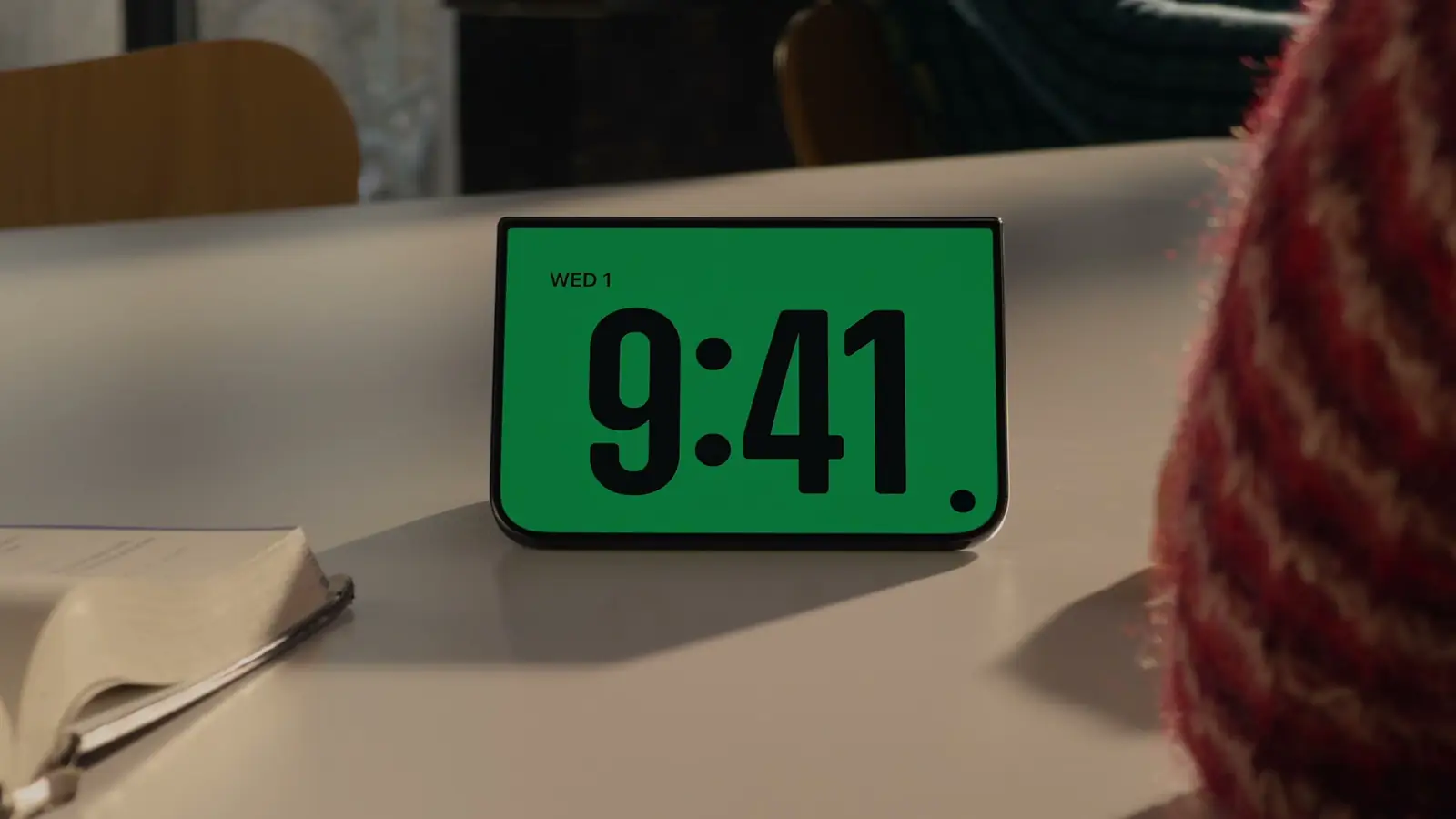 The foldable iPhone standing half-open on a desk like a small tent, its screen showing a large 9:41 clock