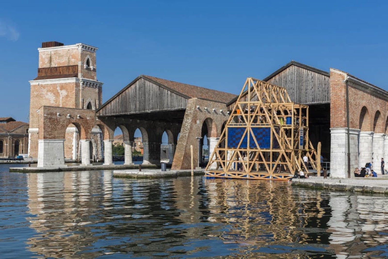 Die zweite Iteration des Makoko Floating System (MFS II) liegt an den Gaggiandre-Werften der Architekturbiennale Venedig vor Anker, mit den Backsteinbögen des Arsenale dahinter