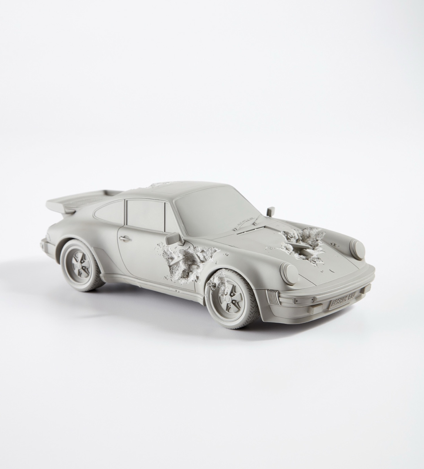 Reprodução erodida de um Porsche 911 Turbo em selenita e quartzo, com cavidades minerais rompendo a carroceria