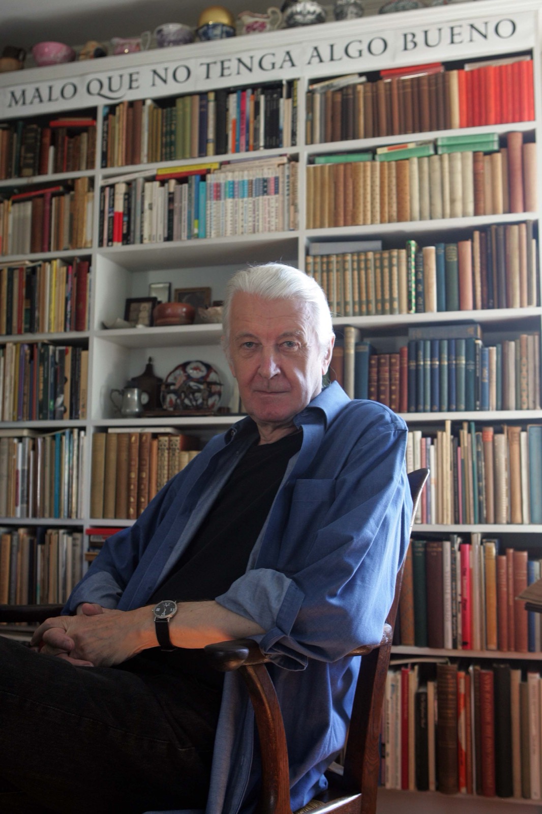 Matthew Carter sentado na biblioteca de sua casa em Cambridge, Massachusetts, com letras tipográficas visíveis acima das estantes atrás dele