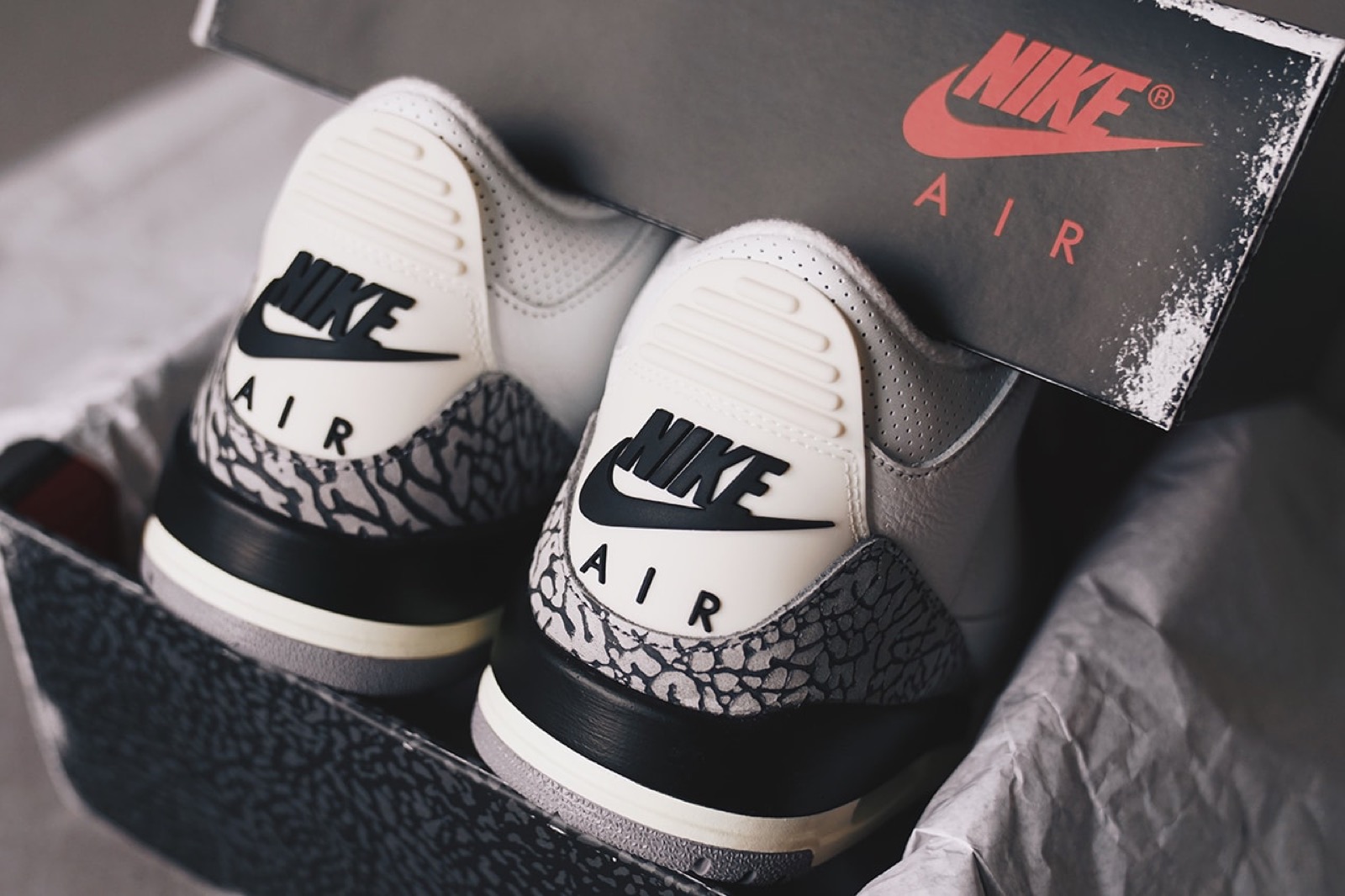 Par de Air Jordan III White Cement, mostrando o logo Jumpman, o couro tumbled e a estampa cinza de elefante