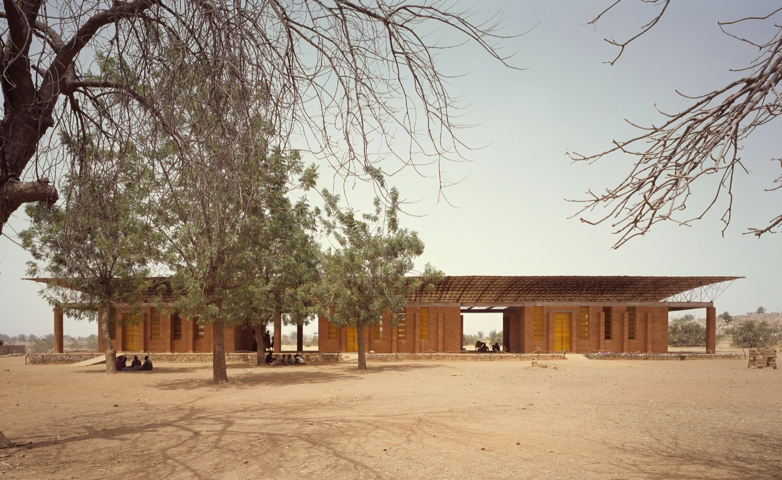 Außenansicht der Gando Primary School in Burkina Faso, mit dem aufgeständerten Wellblechdach über Wänden aus verdichteter Erde