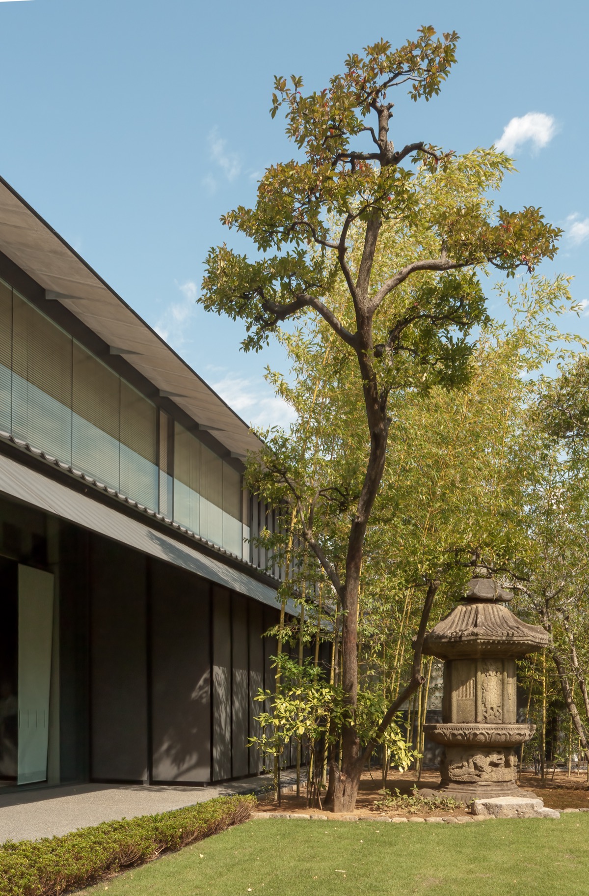 The Nezu Museum's low eaves meeting its garden, a stone pagoda among the trees