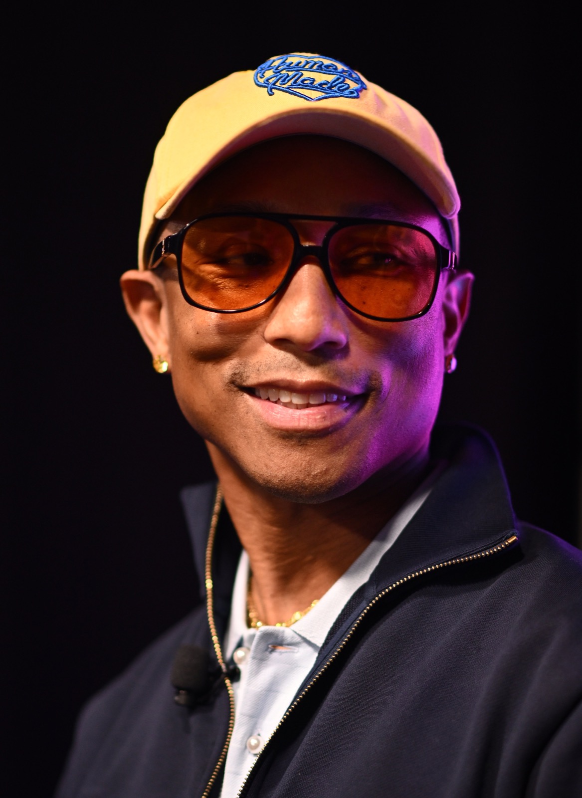 Pharrell Williams em 2024, usando um boné Human Made bege e óculos escuros com lentes âmbar