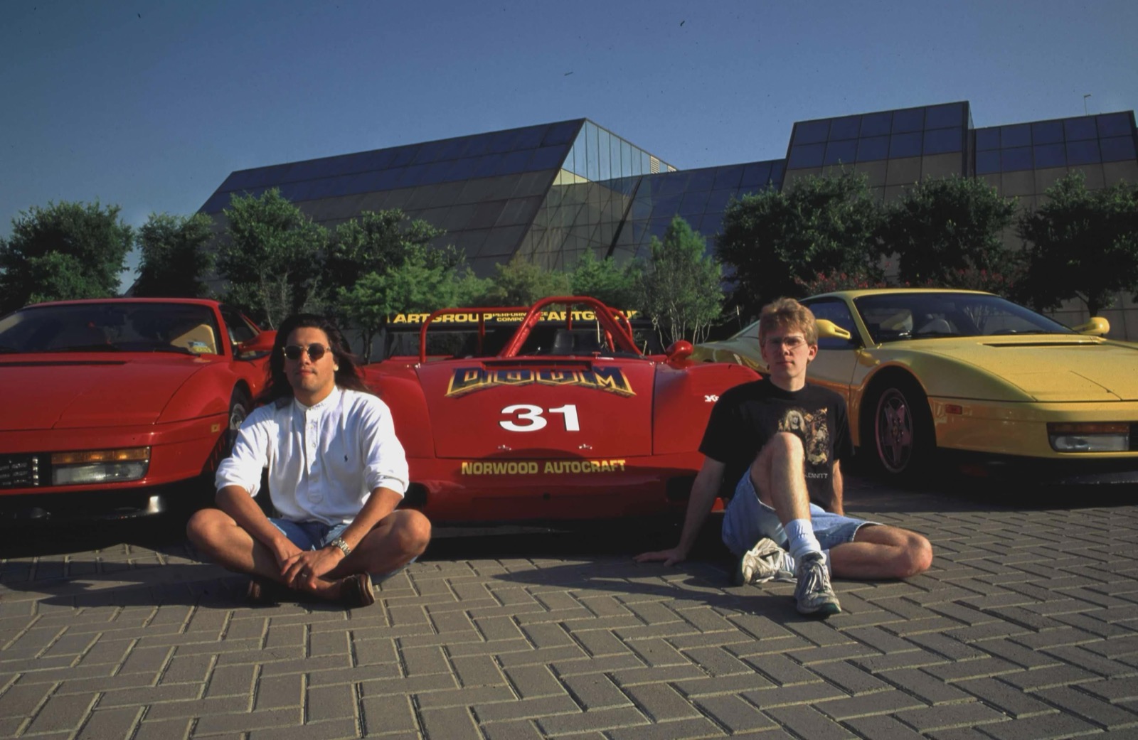John Romero (left) and John Carmack with their Ferraris outside the id Software offices in the early 1990s, including a DOOM-liveried race car