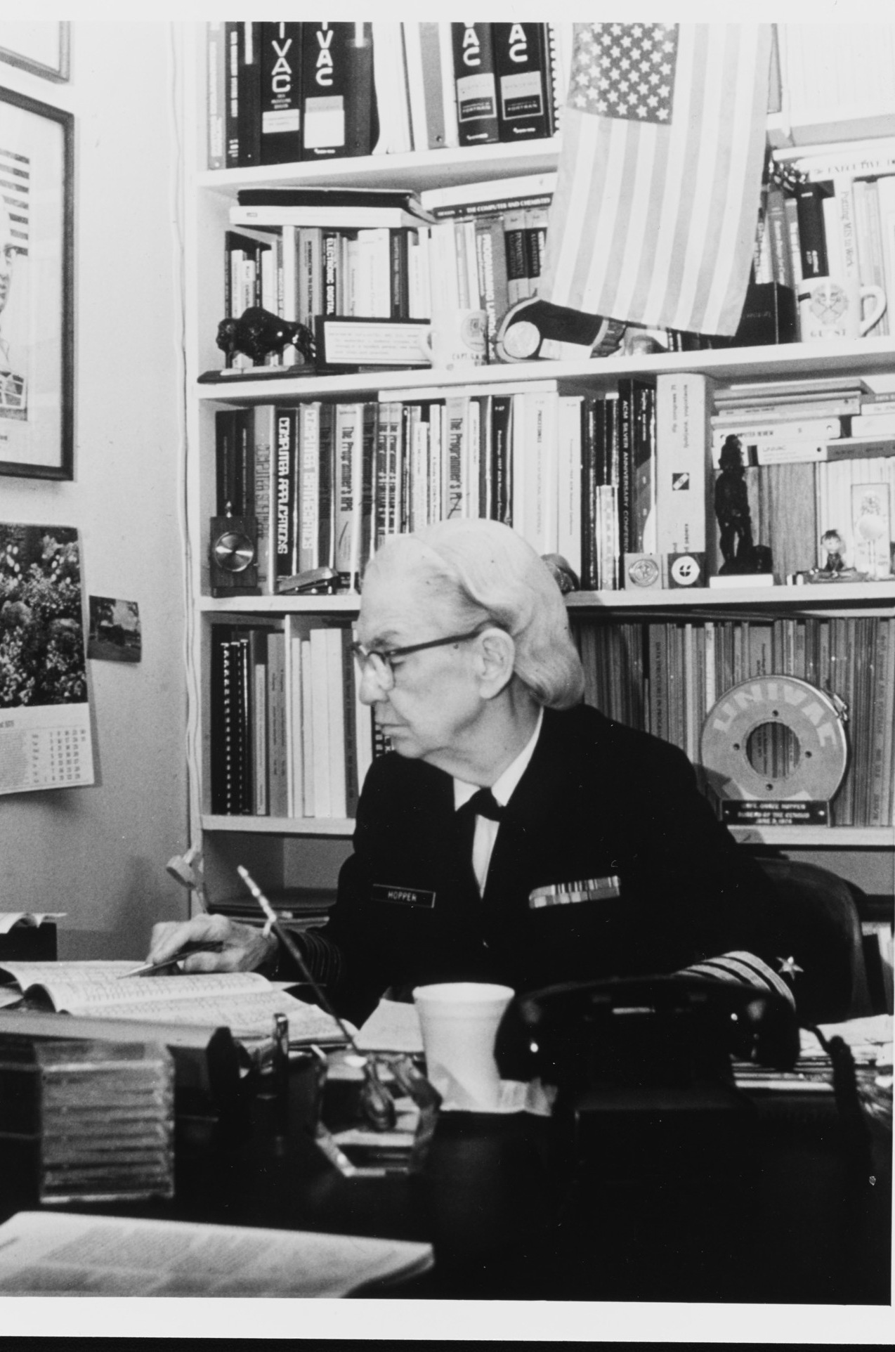 Grace Hopper at work, surrounded by UNIVAC manuals and a magnetic-tape reel